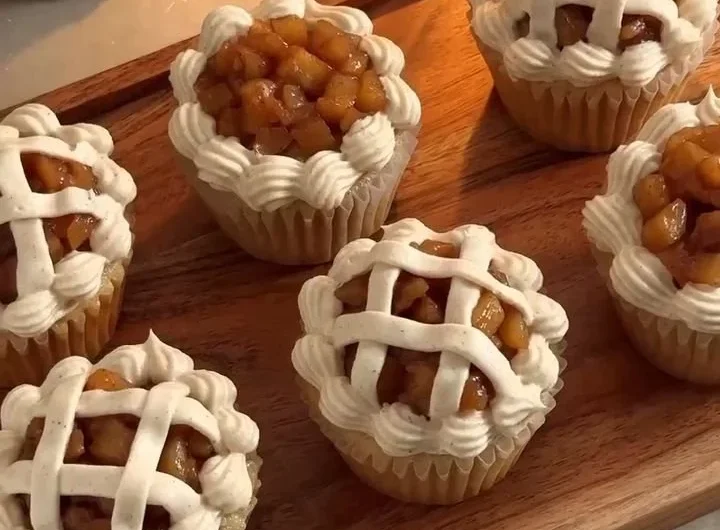 Apple pie cupcakes topped with frosting and apple slices.