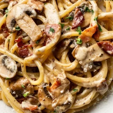 Creamy bacon and mushroom pasta dish garnished with parsley