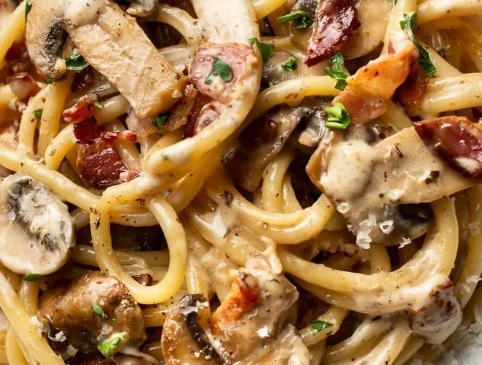 Creamy bacon and mushroom pasta dish garnished with parsley