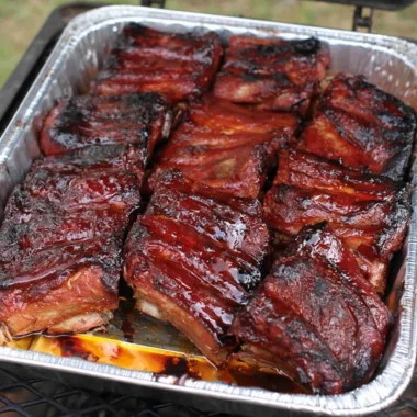 Delicious BBQ ribs served on a platter with sauce and sides.