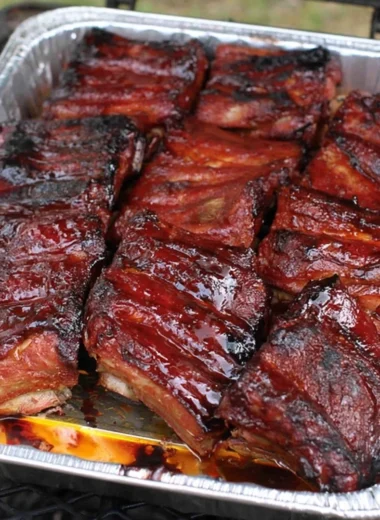 Delicious BBQ ribs served on a platter with sauce and sides.