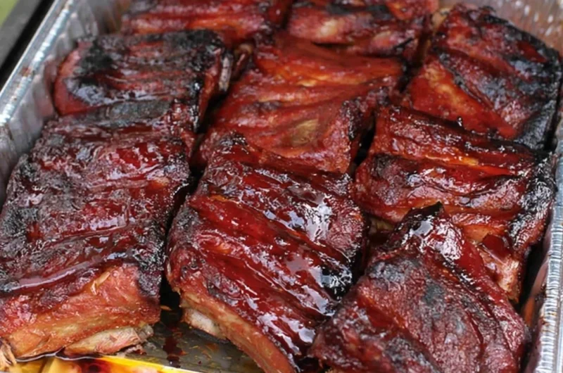 Delicious BBQ ribs served on a platter with sauce and sides.