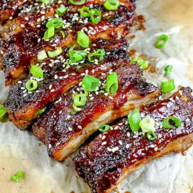 Delicious sticky Asian ribs served on a plate, showcasing rich glaze and garnishes.