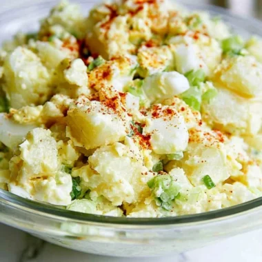 Delicious potato salad with egg served in a bowl garnished with herbs.