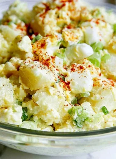 Delicious potato salad with egg served in a bowl garnished with herbs.