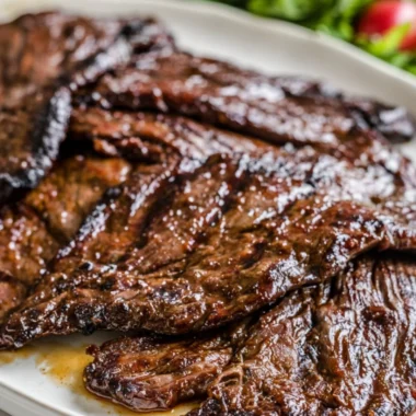 Citrus marinated grilled flank steak served on a plate with fresh herbs.