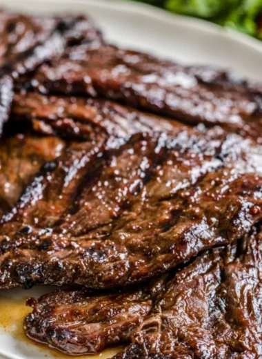 Citrus marinated grilled flank steak served on a plate with fresh herbs.