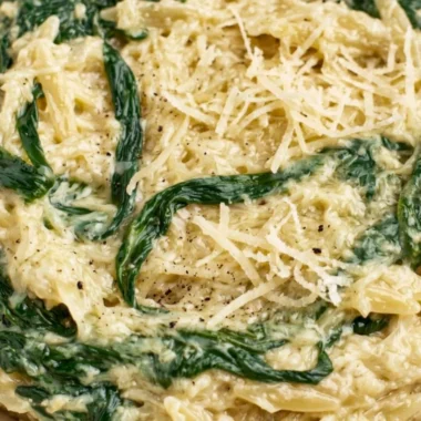 Creamy garlic spinach orzo dish served in a bowl, garnished with herbs.