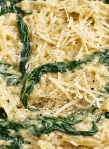 Creamy garlic spinach orzo dish served in a bowl, garnished with herbs.