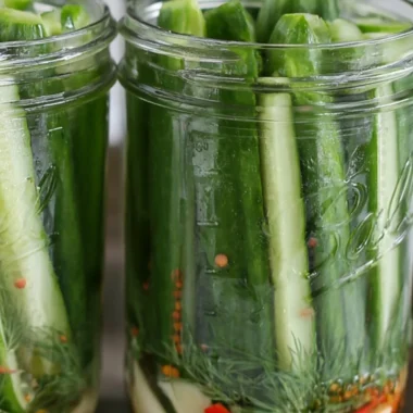 Batch of crispy dill pickles in a mason jar on a wooden table