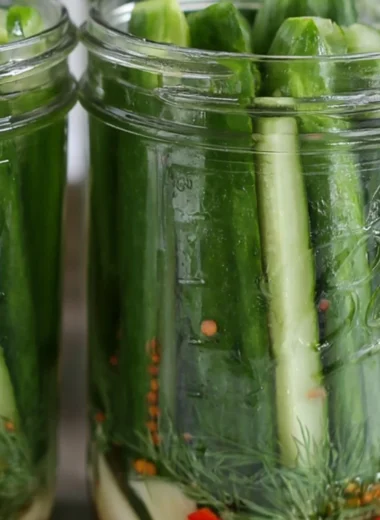 Batch of crispy dill pickles in a mason jar on a wooden table
