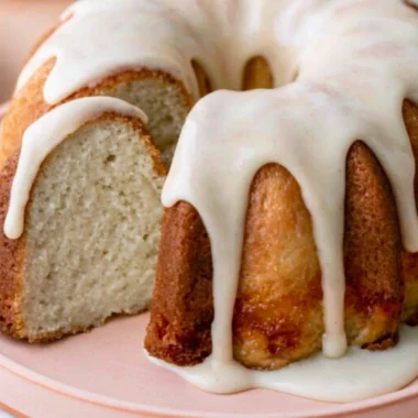 Moist vanilla bundt cake drizzled with icing on a decorative plate