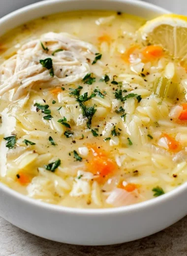 Bowl of Easy Lemon Chicken Orzo Soup garnished with herbs