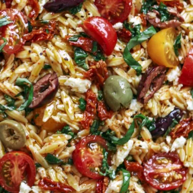 Delicious Greek Orzo salad with tomatoes, olives, basil, and feta cheese.