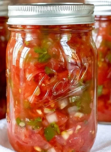 Homemade salsa in jars ready for canning with fresh tomatoes and herbs