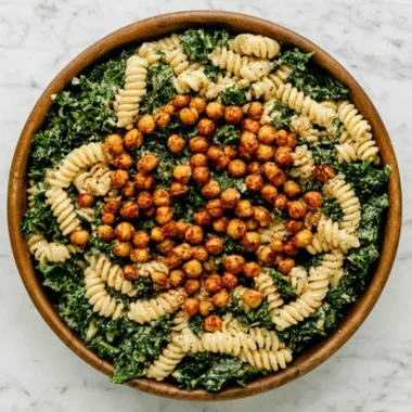 A vibrant Kale Caesar Pasta Salad topped with croutons and parmesan cheese.