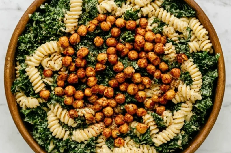 A vibrant Kale Caesar Pasta Salad topped with croutons and parmesan cheese.