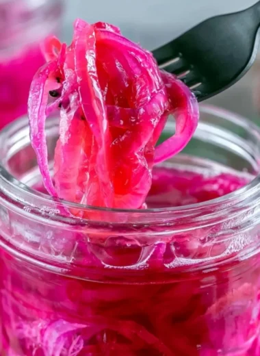 Jar of quick pickled red onions with spices and herbs