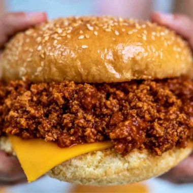 Slow cooker sloppy joes served in a bun with toppings.