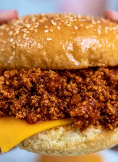 Slow cooker sloppy joes served in a bun with toppings.