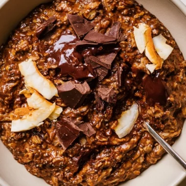 A bowl of creamy chocolate oatmeal topped with fresh berries and nuts.