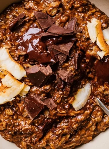 A bowl of creamy chocolate oatmeal topped with fresh berries and nuts.